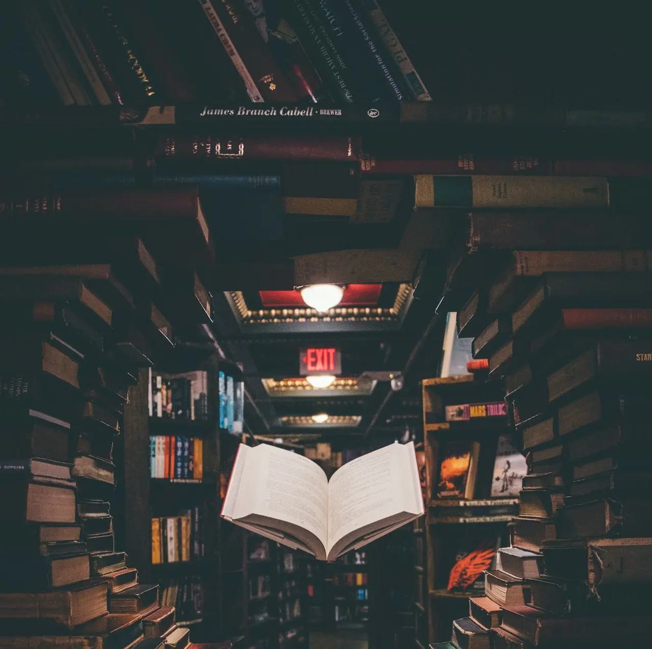 view of floating open book from stacked books in library